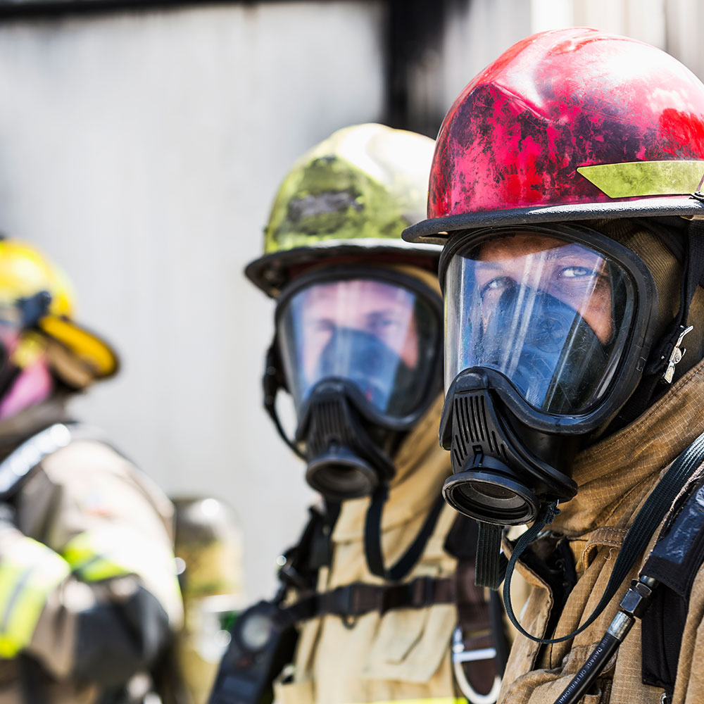 Three firefighters wearing oxygen masks